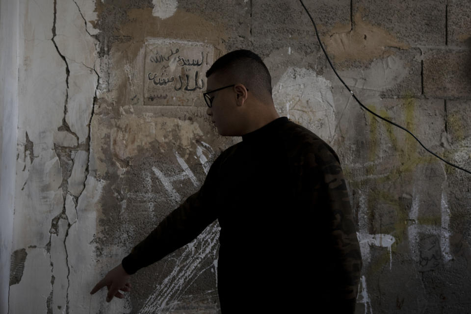 Yousef Mesheh, 15, points to damage to a wall when Israeli forces stormed into his home at 3.a.m., in the Balata Refugee Camp in the northern West Bank, Tuesday, Jan. 10, 2023. A report to be released next Monday by Israeli human rights organization HaMoked found that the Israeli military arrested and interrogated hundreds of Palestinian teenagers in 2022 in the occupied West Bank, without ever issuing a summons or notifying their families.(AP Photo/ Maya Alleruzzo)