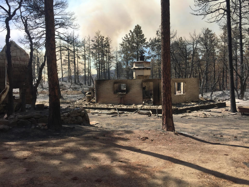 This photo provided by Rusty Bowers shows the remains of Arizona House Speaker Rusty Bowers' family weekend home near several miles southeast of Miami, Ariz., Tuesday, June 8, 2021, that was destroyed by a wildfire the day before. Bowers used the home in the remote mountains as a family retreat and often did his artwork there. (Elijah Cardon/Rusty Bowers via AP)