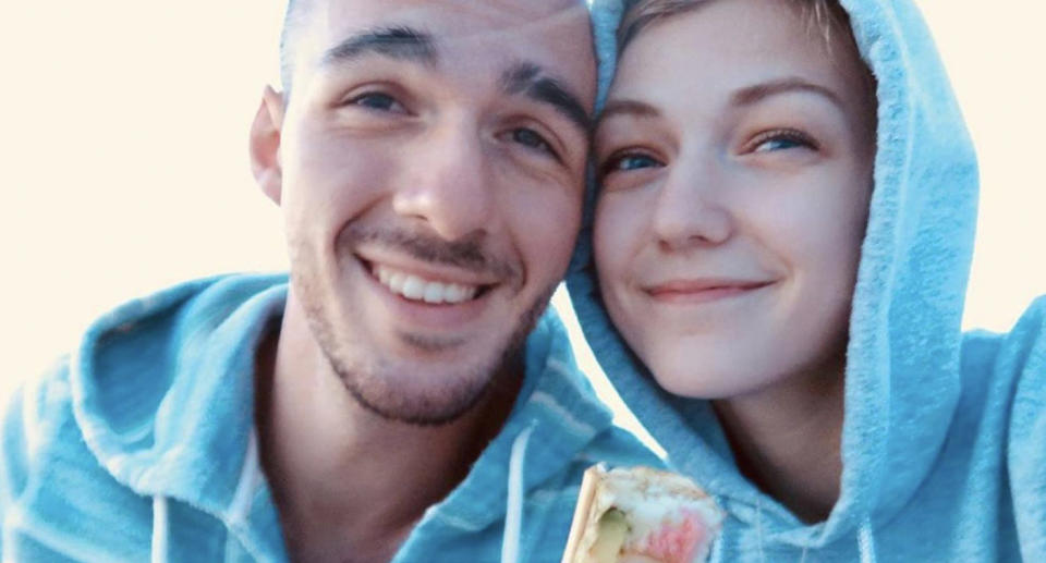 Brian Laundrie and his fiancee Gabby Petito wearing blue towels smiling at camera.