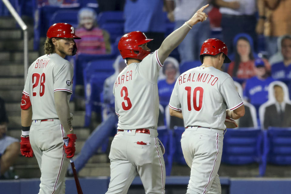 Philadelphia Phillies' Bryce Harper (3) gestures to Rhys Hoskins (not shown) whose double scored three runs as Alec Bohm (28) and J.T. Realmuto react during the seventh inning of a baseball game against the Toronto Blue Jays, Friday, May 14, 2021, in Dunedin, Fla. (AP Photo/Mike Carlson)