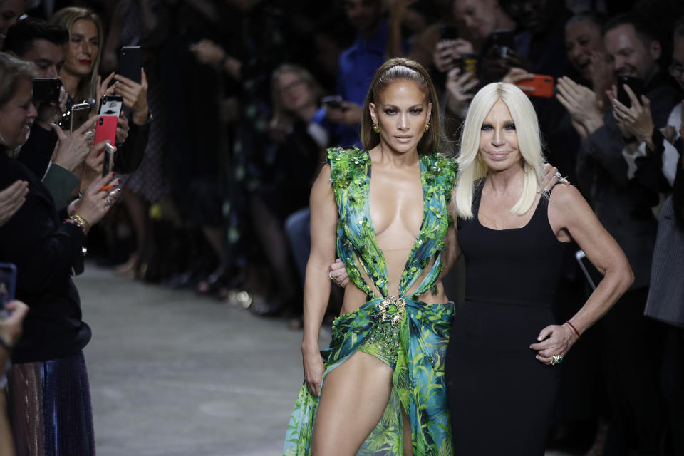 Actress Jennifer Lopez, left, and designer Donatella Versace accept applause at the conclusion of the Versace Spring-Summer 2020 collection, unveiled during the fashion week, in Milan, Italy, Friday, Sept. 20, 2019. (AP Photo/Luca Bruno)