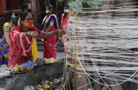 A woman perform rituals with ceremonial thread around a banyan tree on Vat Savitri festival in Mumbai, India, Friday, June 5, 2020. Vat Savitri is celebrated on a full moon day where women pray for the longevity of their husbands. (AP Photo/Rajanish Kakade)