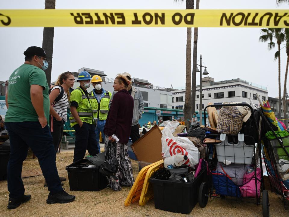 Dixie Moore (R) talks with representatives from St Joseph Center Homeless Services who will help her move from her tent encampment along the Venice Beach Boardwalk, to short-term housing in a nearby hotel July 2, 2021 in Los Angeles, California.