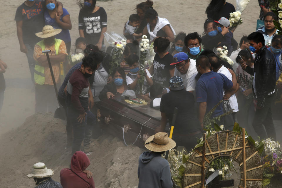 Relatives bury their loved one at the newly constructed Valle de Chalco Municipal Cemetery, built to accommodate the rise in deaths amid the new coronavirus pandemic, on the outskirts of Mexico City, Thursday, May 21, 2020. Funeral parlors and crematoriums in Valle de Chalco say they have seen their work multiplied with the surging number of dead from COVID-19. (AP Photo/Marco Ugarte)