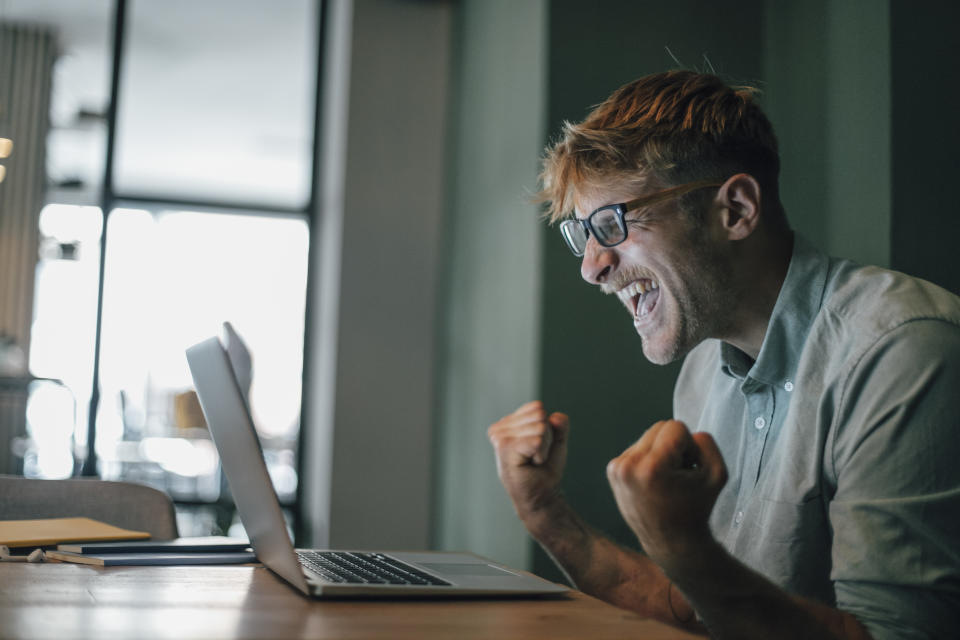 Young man using laptop, laughing happily. (Photo: Getty)