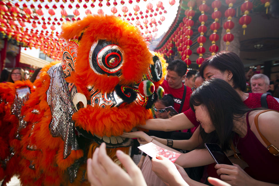 Temple visitors give red packets to the lion dance troupe during the lion dance performance on the first day of Chinese Lunar New Year at a temple in Kuala Lumpur, Malaysia, Saturday, Jan. 28, 2017. The celebration marks the Year of the Rooster in the Chinese calendar. (AP Photo/Lim Huey Teng)