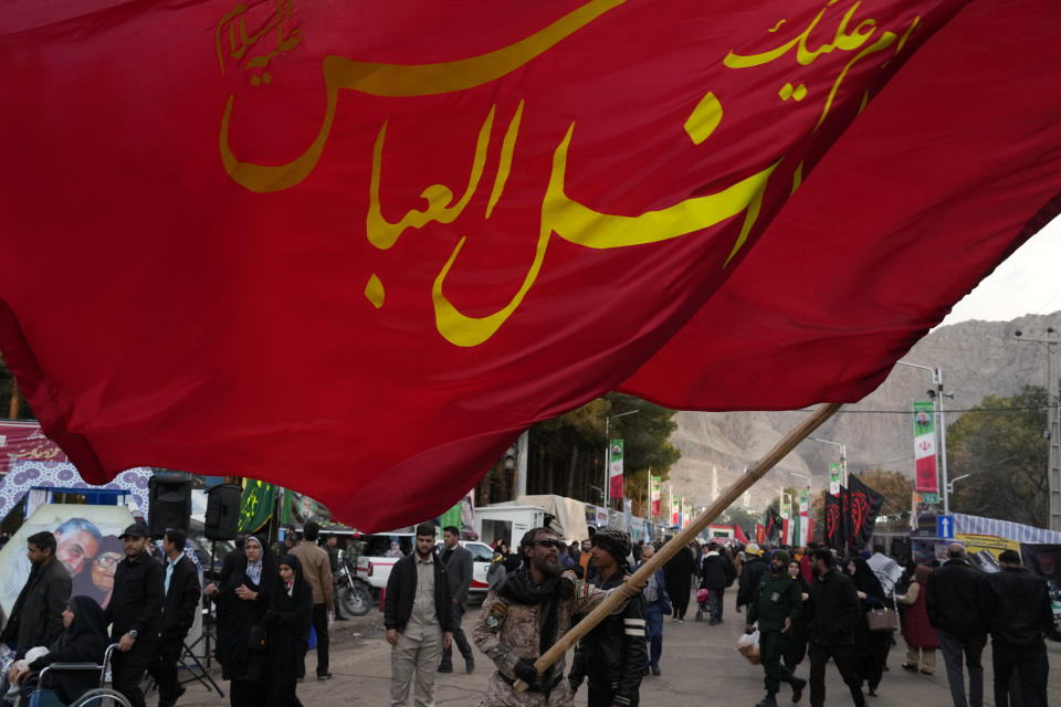 A man waves a huge flag carrying the name of Shiite Saint Abolfazl on the street towards the grave of the late Iranian Revolutionary Guard Gen. Qassem Soleimani in the city of Kerman about 510 miles (820 kms) southeast of the capital Tehran, Iran, Thursday, Jan. 4, 2024. Investigators believe suicide bombers likely carried out an attack on a commemoration for an Iranian general slain in a 2020 U.S. drone strike, state media reported Thursday, as Iran grappled with its worst mass-casualty attack in decades and as the wider Mideast remains on edge. (AP Photo/Vahid Salemi)
