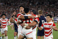 Japan's Kenki Fukuoka is congratulated by his teammates after scoring his team's third try during the Rugby World Cup Pool A game at International Stadium between Japan and Scotland in Yokohama, Japan, Sunday, Oct. 13, 2019. (AP Photo/Christophe Ena)