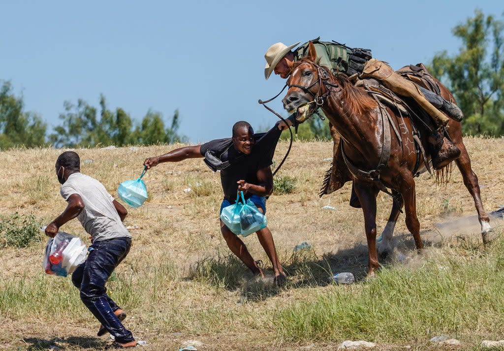 A US border patrol officer corrals a Haitian migrant earlier in September  (AFP via Getty)