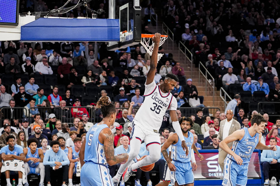 UConn forward Samson Johnson (35) hangs on the rim after dunking the ball during the first half of an NCAA college basketball game against North Carolina in New York, Tuesday, Dec. 5, 2023. (AP Photo/Peter K. Afriyie)