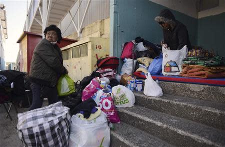 A resident, whose home was damaged in a major fire, arranges her belongings on the steps of a shelter for victims of the blaze, in Valparaiso, April 14, 2014. REUTERS/Lucas Ninno