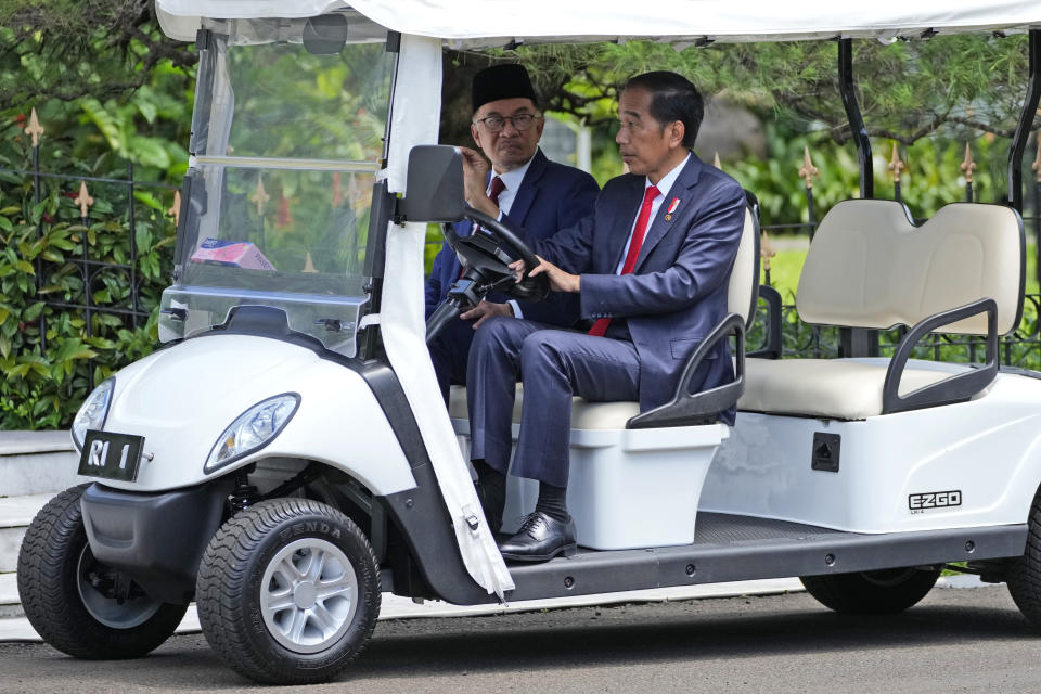 Indonesian President Joko Widodo, right, talks with Malaysian Prime Minister Anwar Ibrahim as they ride a golf cart during their meeting at the presidential palace in Bogor, West Java, Indonesia, Monday, Jan. 9, 2023. (AP Photo/Achmad Ibrahim)