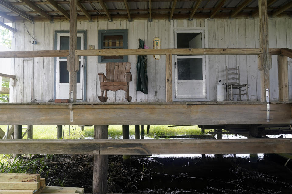 A rocking chair sits on the porch of an old trapper's camp that has been restored and repurposed by the McIlhenny Company, on Avery Island, La., where Tabasco brand pepper sauce is made, Tuesday, April 27, 2021. As storms grow more violent and Louisiana loses more of its coast, the family that makes Tabasco Sauce is fighting erosion in the marshland that buffers its factory from hurricanes and floods. (AP Photo/Gerald Herbert)