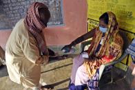 A woman wearing a face mask as a protective measure against the coronavirus helps voters sanitize their hands at a polling station, during the first phase of state elections at Paliganj, in the eastern Indian state of Bihar, Wednesday, Oct. 28, 2020. With an overall declining coronavirus positive trend, Indian authorities decided to hold the first state legislature election since the outbreak of COVID-19. People began voting Wednesday in the country’s third largest state Bihar with of a population of about 122 million people. (AP Photo/Aftab Alam Siddiqui)