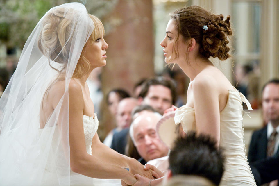 Anne Hathaway and Kate Hudson hold hands in bridal gowns