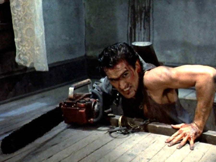 Bruce Campbell as Ash Williams with a chainsaw attached to his arm.