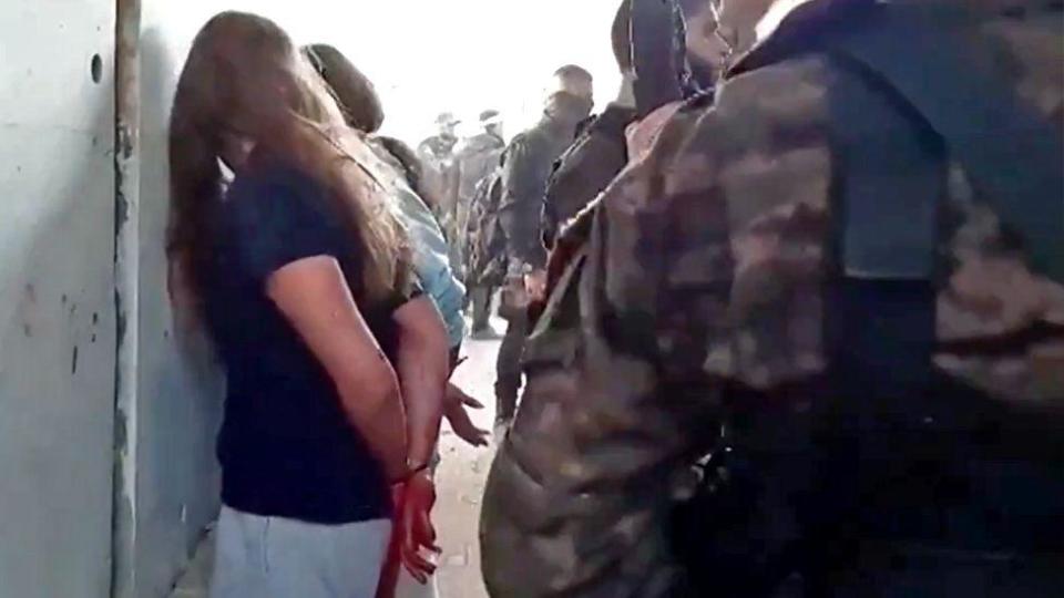 Israeli hostage Naama Levy (L) is seen with her hands tied and facing a wall while Hamas gunmen stand next to her in newly released video filmed by Hamas gunmen at the Nahal Oz base on October 7 ( May 22, 2024)