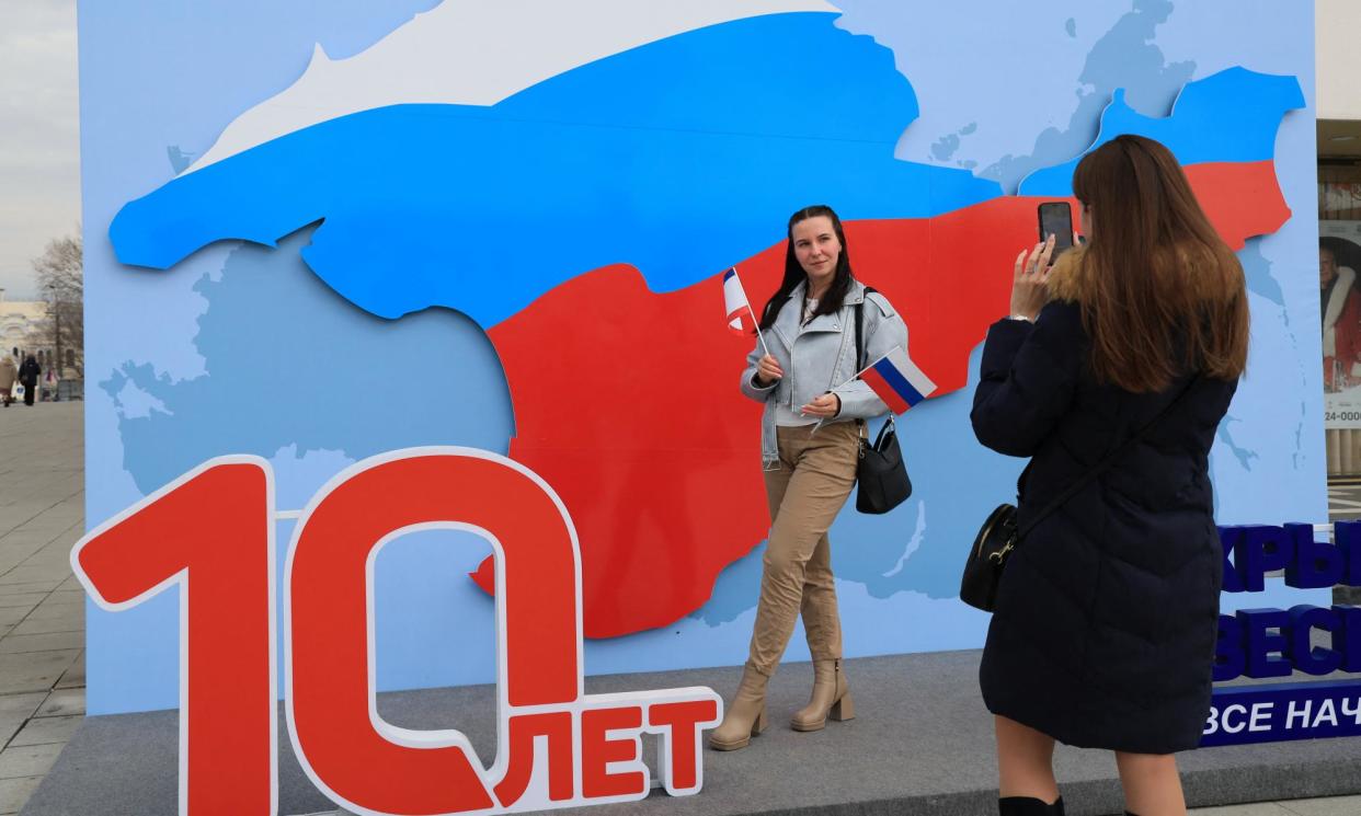 <span>A woman poses for a picture by a map of the Crimean peninsula in the colours of the Russian flag.</span><span>Photograph: AFP/Getty Images</span>