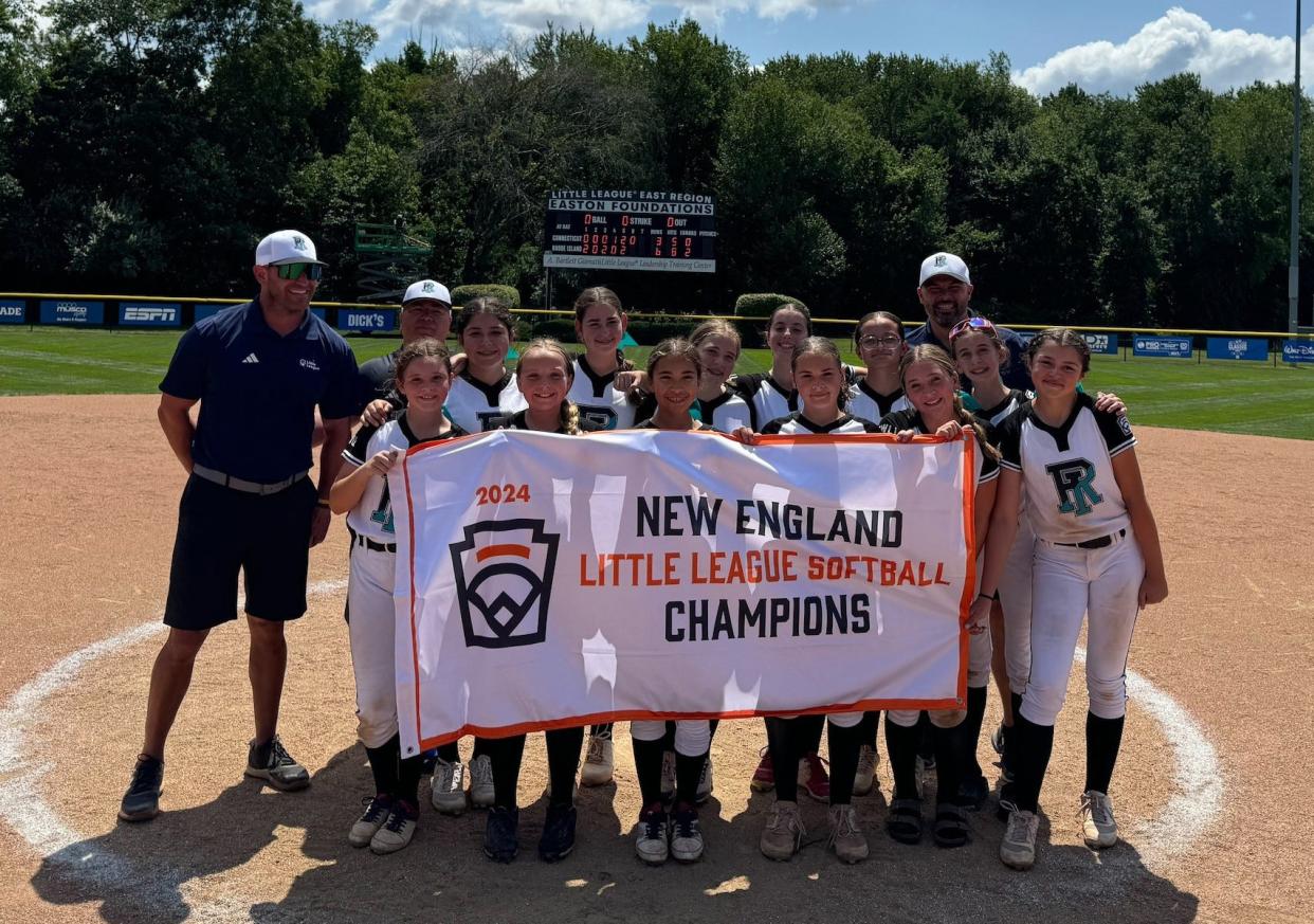 The Rhode Island state champion Cranston Western Little League holds their New England championship banner after beating Connecticut on Friday for the regional title.The team now qualifies for the Little League Softball World Series.