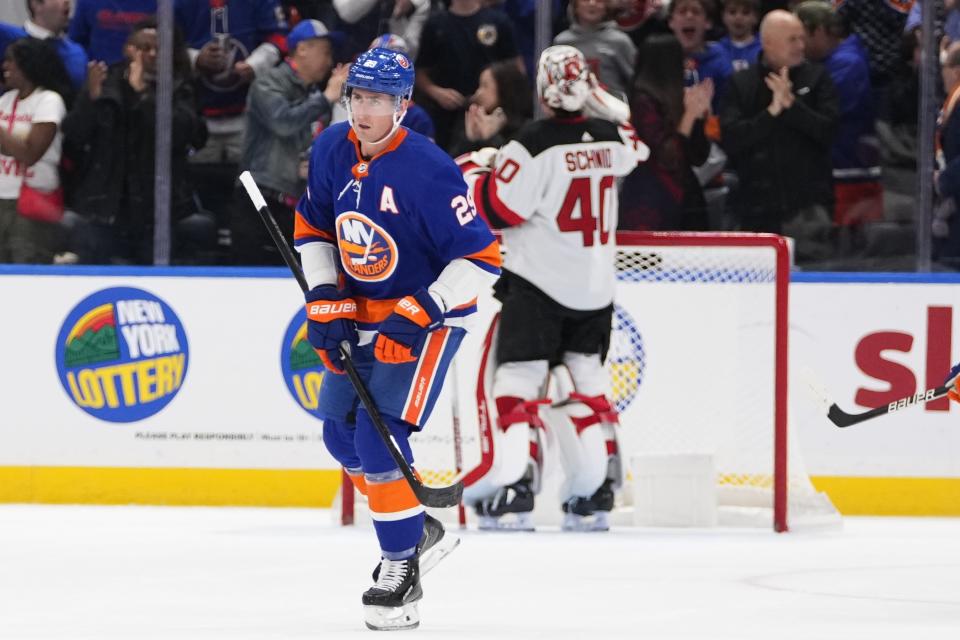 New York Islanders' Brock Nelson, left, skates past New Jersey Devils goaltender Akira Schmid after scoring a goal during the first period of an NHL hockey game Friday, Oct. 20, 2023, in Elmont, N.Y. (AP Photo/Frank Franklin II)