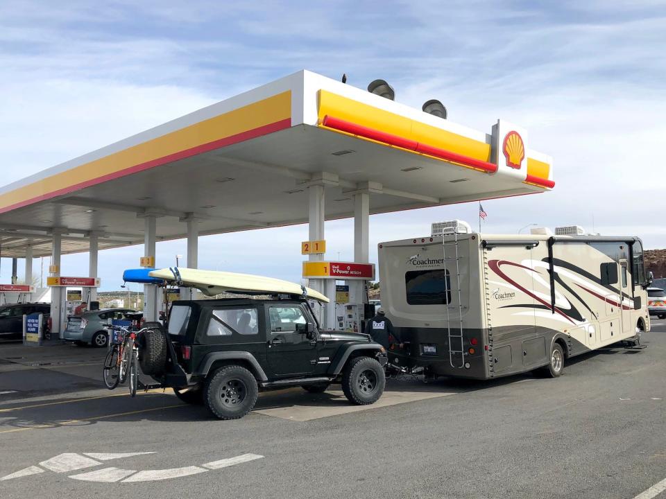 A recreational vehicle stops for gas and is fully prepared for a road trip with an RV, Jeep, Kayak and bicycles April 4 2019, Kingman, Arizona