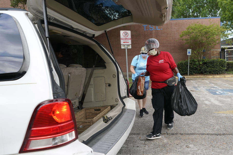 Vicky Dickson, with Houston Independent School District Nutrition Services, loads a bag of food into a car Monday, April 6, 2020, in Houston. HISD relaunched their food distribution efforts throughout the district Monday, with a streamlined process that will implement increased safety measures. (AP Photo/David J. Phillip)