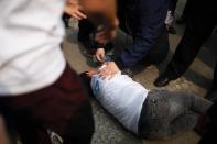 Protesters assist a relative of one of the MH370 passengers who fainted during a demonstration outside the Malaysian embassy in Beijing, on March 25, 2014