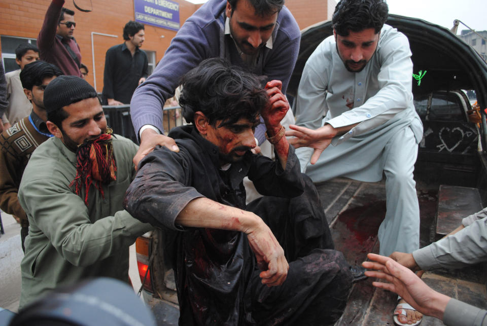 People carry an injured person to a local hospital in Peshawar, Pakistan, Friday, March 14, 2014. Pakistani officials said a suicide attacker has blown himself up near a police armored vehicle outside the northwestern city of Peshawar, killing several people. (AP Photo/Mohammad Sajjad)