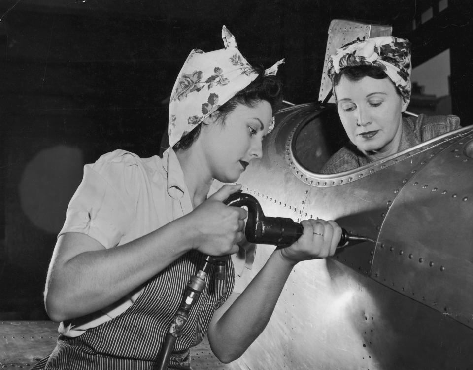 American female workers drive rivets into an aircraft circa 1943