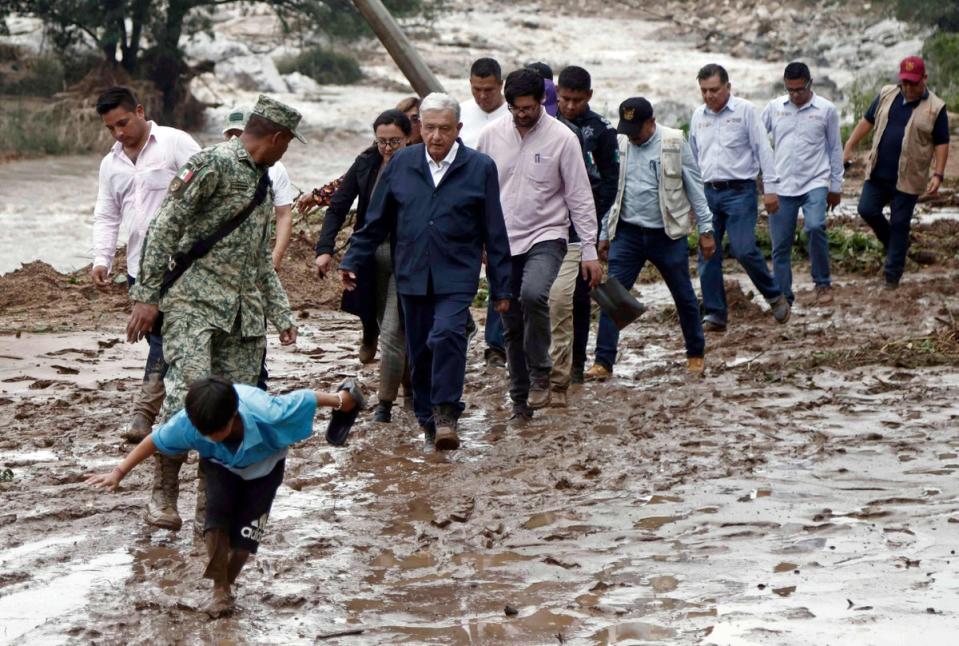 Lopez Obrador and members of his cabinet walk through mud as they visit the Kilometro 42 community, near Acapulco (AFP via Getty Images)