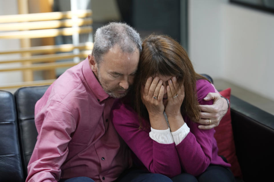 Simon Glass, left, and his wife, Sally Glass, embrace as they talk about the $19 million settlement from state and local law enforcement agencies for the killing of the couple's 22-year-old son, Christian, in June 2022, while he suffered a mental health crisis Tuesday, May 23, 2023, during a news interview in the offices of the couple's lawyers in Denver. As part of the settlement, training for law officers will change as well. (AP Photo/David Zalubowski)