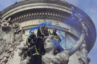 Firemen use blue flares atop a statue as they protest with hospital staff on wages, working conditions and pensions, Tuesday, Oct. 15, 2019 in Paris. (AP Photo/Michel Euler)