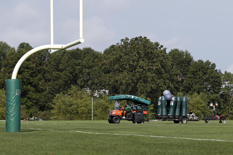 Empty Jets practice field with uprights, cart carrying equipment. 