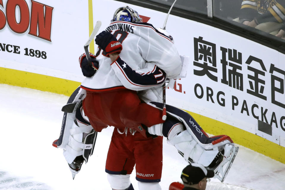 Columbus Blue Jackets goaltender Elvis Merzlikins (90) jumps into the arms of teammate Nick Foligno (71) to celebrate their victory over the Boston Bruins in the overtime period of an NHL hockey game, Thursday, Jan. 2, 2020, in Boston. (AP Photo/Elise Amendola)