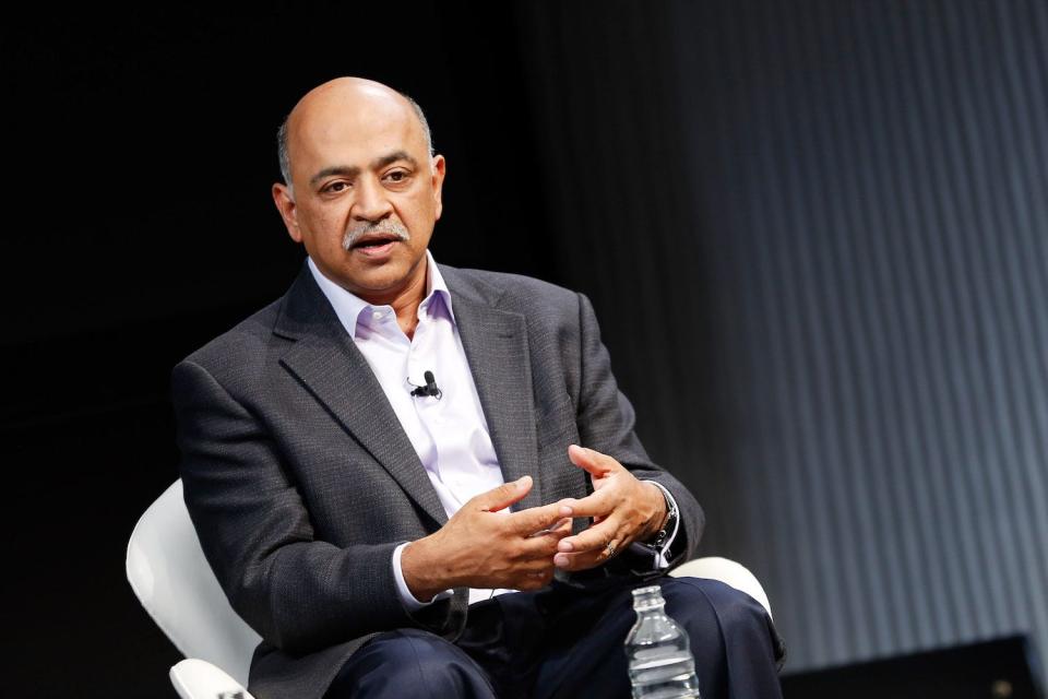 Arvind Krishna speaking to a crowd while sitting in a chair with his hands together.