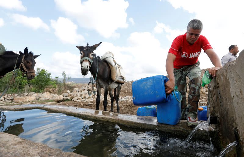 FILE PHOTO: A man fills containers with water from a well, which are transported home on his donkey in Oued al-Berber, Tunisia