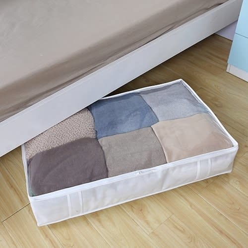 Under-bed storage container holding neatly folded blankets to optimize space