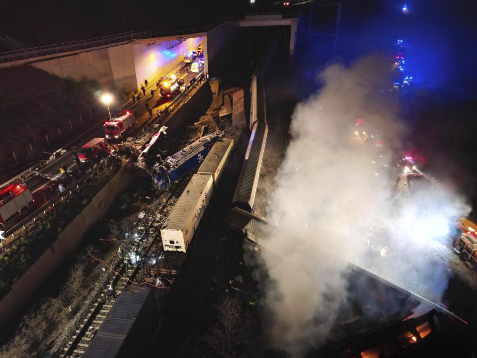 Smoke rises from trains as firefighters and rescuers operate after a collision near Larissa city, Greece, early Wednesday, March 1, 2023. The collision between a freight and passenger train occurred near Tempe, some 380 kilometers (235 miles) north of Athens, and resulted in the derailment of several train cars. (AP Photo/Vaggelis Kousioras)