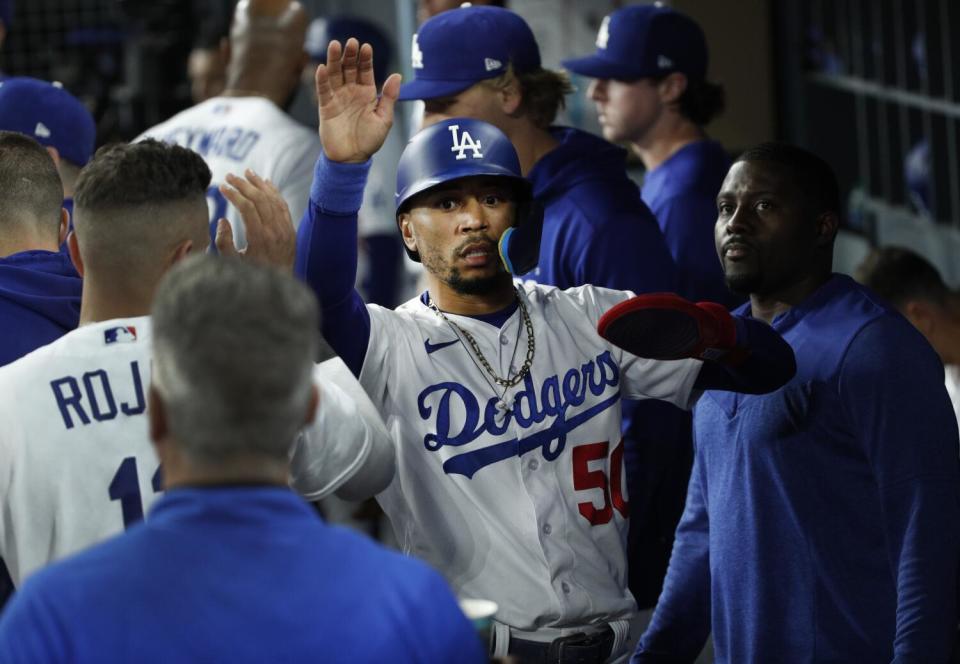 Dodgers right fielder Mookie Betts gets high-fives in the dugout after scoring against the Giants on Saturday.