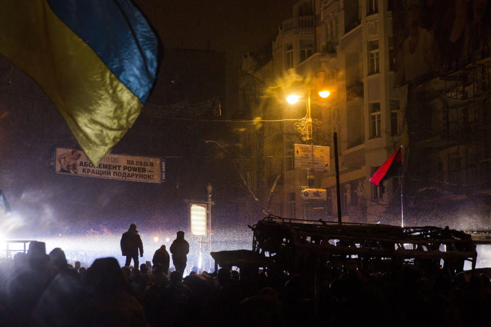 Protesters stand on the barricade during clashes with police in central Kiev, Ukraine, early Wednesday, Jan. 22, 2014. The mass protests in Kiev, the capital, erupted after Ukrainian President Viktor Yanukovych spurned a pact with the European Union in favor of close ties with Russia, which offered him a $15 billion bailout. (AP Photo/Evgeny Feldman)