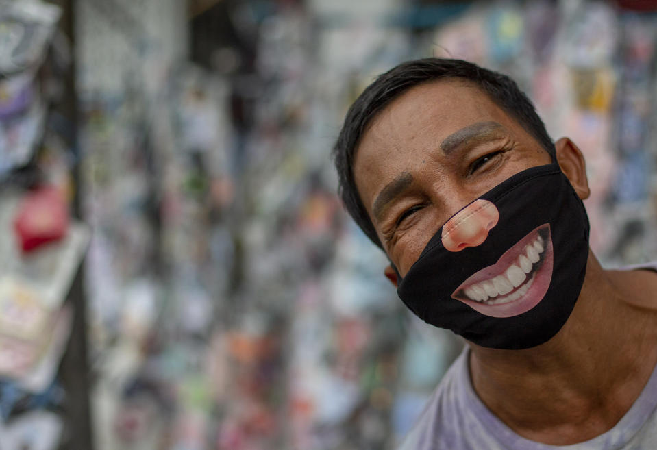 A mask seller wearing a mask stands in a street market in Bangkok, Thailand, Tuesday, June 9, 2020. Daily life in capital resuming to normal as Thai government continues to ease restrictions related to running business in capital Bangkok that were imposed weeks ago to combat the spread of COVID-19. (AP Photo/ Gemunu Amarasinghe)