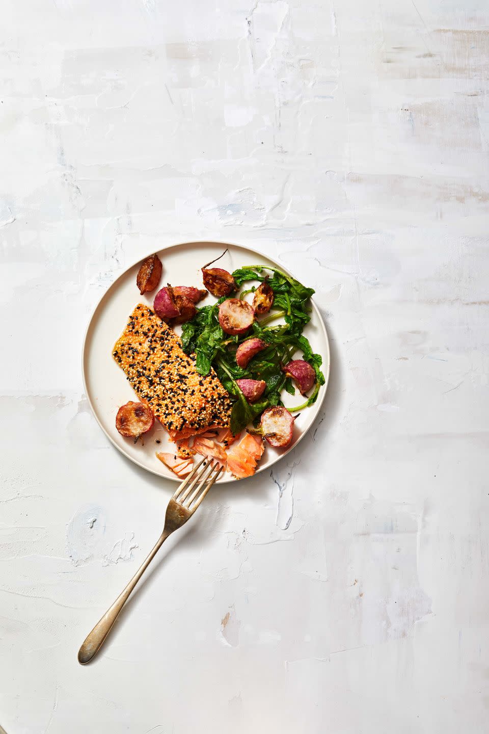 sesame crusted salmon with roasted radishes on a white plate