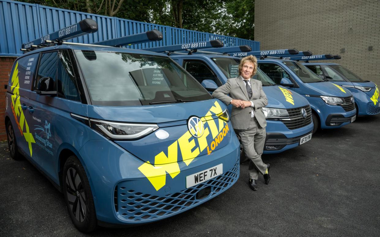 Mr Mullins leans against one of a row of liveried vans used by one of his businesses