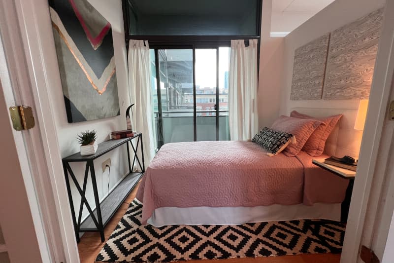 Neatly made bed in staged condo bedroom.