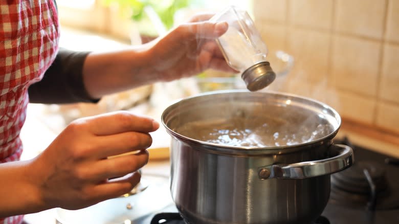 Woman salting boiling water