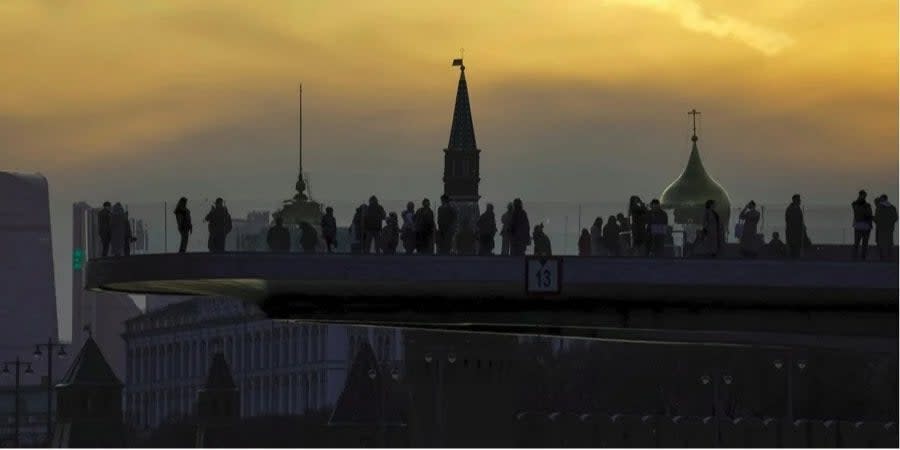 A group of people watching the sunset in front of the Kremlin