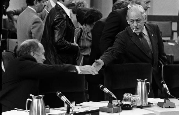 Prime Minister Pierre Trudeau stretches to shake hands with  Quebec Premier René Lévesque at the start of the meeting of the first ministers in Ottawa Nov. 2, 1981.At this set of talks, the provinces made their support for constitutional reforms contingent on the inclusion of a 'notwithstanding clause.'