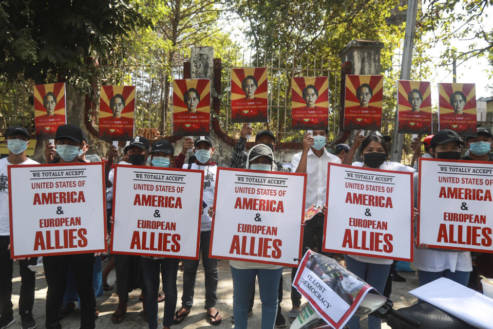 Anti-coup protesters hold posters with an image of deposed Myanmar leader Aung San Suu Kyi as others hold signs that read: "We totally accept United States of America and European allies" as they gather outside the U.N. Information Office in Yangon, Myanmar, Sunday, Feb. 14, 2021. Vast numbers of people all over Myanmar have flouted orders against demonstrations to march again in protest against the military takeover that ousted the elected government of Suu Kyi. (AP Photo)