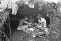 FILE - Music fans seek shelter is a grass hut at the Woodstock Music and Art Festival in Bethel, N.Y., Aug. 17, 1969. The sign above reads "Have a Marijuana." (AP Photo, File)