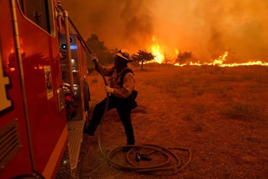 Robert Ortiz of Los Angeles County Fire works around a fire engine while protecting a home from the advancing Bobcat Fire along Cima Mesa Rd. Friday, Sept. 18, 2020, in Juniper Hills, Calif. (AP Photo/Marcio Jose Sanchez)